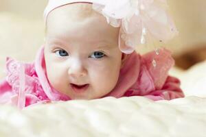poco tre mese vecchio ragazza con blu occhi nel rosa pagare. foto