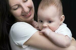 bellissimo madre abbracci sua bambino. maternità.mamma e poco figlio su un' buio sfondo. maternità. foto