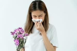 polline allergie, asiatico giovane donna starnuti nel un' fazzoletto o soffiaggio nel un' pulire, allergico per selvaggio primavera fiori o fiori durante primavera. allergico reazione, respiratorio sistema i problemi foto