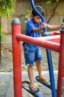 asiatico ragazzo fare routine esercizio nel società parco durante il mattina volta. carino poco ragazzo esercizio e Palestra per mantenere lui stesso in forma per vita. del bambino esercizio all'aperto sparare foto