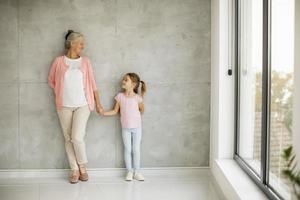 nonna che tiene la mano della nipote vicino a una finestra foto