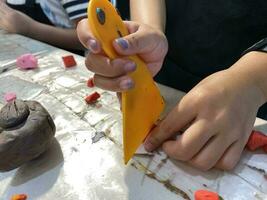 vicino su mani bambino taglio argilla per scultura. foto