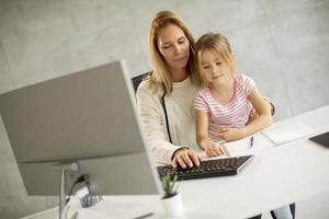 madre che scrive con la figlia in grembo foto