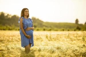 donna incinta in abito blu alla luce del sole dorato foto