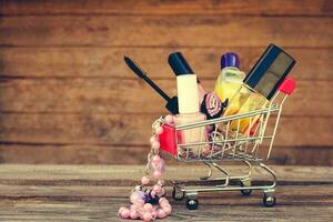 shopping carrello con cosmetici, perline su il vecchio legna sfondo. tonica Immagine. foto