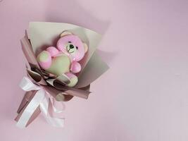 bello rosa orso Bambola nel involucro carta, Usato come un' regalo. romantico concetto e amore detti. La madre di giorno foto
