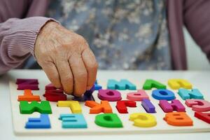 asiatico anziano donna giocando puzzle gioco per pratica cervello formazione per demenza prevenzione, alzheimer patologia. foto