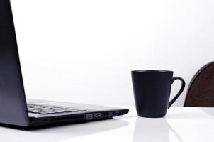 tazza di caffè nero e laptop su sfondo bianco foto