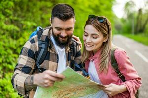 contento coppia escursioni a piedi nel natura e guardare a carta geografica. coppia godendo loro vacanza. foto