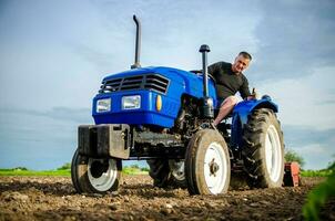 un' contadino su un' trattore pulisce il campo dopo raccolto. preparazione di terra per futuro piantare nuovo Ritaglia. intensivo terra uso. fresatura suolo, allentamento terra prima taglio righe. agricoltura, agricoltura. foto