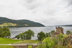 Le persone che si godono la visita al castello di Urquhart sulle rive di Loch Ness in Scozia foto