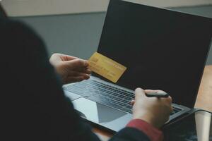 vicino su di donna mano utilizzando credito carta e il computer portatile per pagamento e in linea acquisti, in linea acquisti, pagamenti digitale bancario, e-commerce concetto. foto