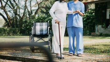 giovane asiatico fisico terapista Lavorando con anziano donna su a piedi con un' camminatore foto