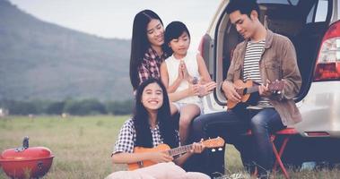 famiglia che suona l'ukulele insieme in campeggio foto