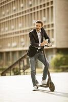 imprenditore tenendo il telefono mentre si sta in piedi su uno scooter foto