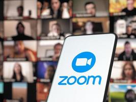 bucarest, romania 2021 - smartphone che avvia l'app per riunioni cloud zoom con riunione su un monitor in background foto