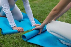 due donne che arrotolano una stuoia di yoga dopo la lezione di yoga foto