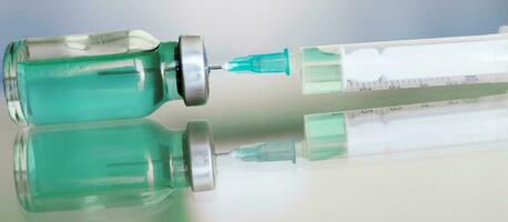 fiala pieno con liquido vaccino nel medico laboratorio con siringa. medico fiala e siringa su il bicchiere superficie. bandiera foto