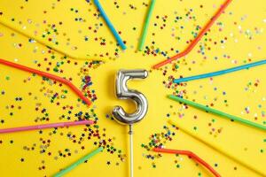 cinque anni compleanno festa. numero cinque con nel modulo di stelle e potabile cannucce su giallo sfondo foto
