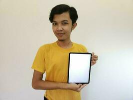 asiatico uomo mostrare con il vuoto schermo di tavoletta foto