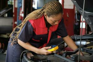 uno nero femmina professionale settore automobilistico meccanico lavoratore controlli un ev auto batteria e ibrido motore a un' Manutenzione box auto, esperto elettrico veicolo servizio, e fissaggio occupazioni auto industria. foto