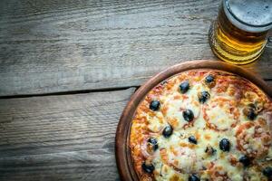 cucinato Pizza con un' bicchiere di birra foto