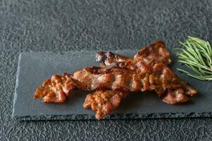 fritte Bacon strisce su il pietra buio tavola foto