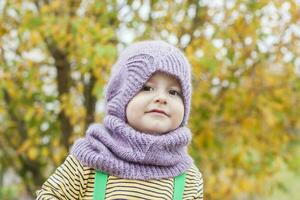 un' bambino nel un' viola, a maglia cappello e sciarpa. foto