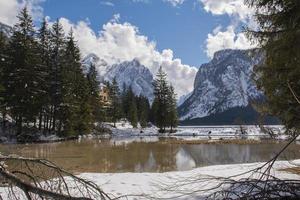 lago alpino tra boschi e montagne innevate foto