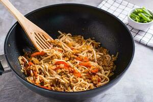 udon tagliatelle con soia carne e verdure nel un' frittura padella su il tavolo foto