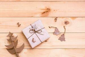 Natale regalo avvolto nel mestiere carta, fatto a mano cartone albero e decorativo alberi su un' naturale di legno sfondo. eco-friendly Natale concetto foto