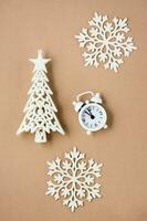 concetto conto alla rovescia su Natale notte. bianca allarme orologio, decorativo Natale albero e i fiocchi di neve su beige cartone. superiore e verticale Visualizza foto