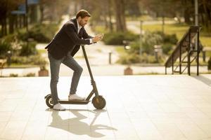 uomo appoggiato su uno scooter e guardando il suo telefono foto