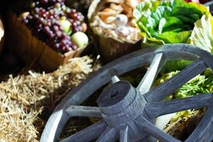 assortimento di verdure fresche su fieno con vecchia ruota di legno