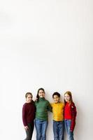 ritratto di simpatici ragazzini in jeans che guarda l'obbiettivo e sorridente mentre in piedi contro il muro bianco foto