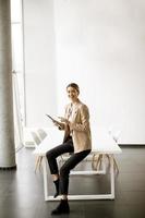 giovane donna che tiene tavoletta digitale in ufficio moderno foto