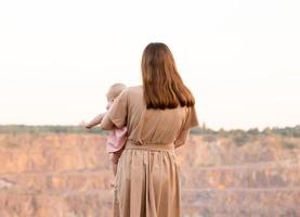 una giovane madre sta guardando la cava o le montagne e tiene in braccio un bambino