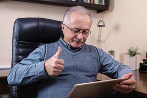 uomo anziano leggendo notizie sulla tavoletta digitale foto