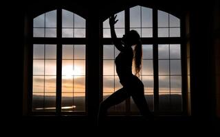silhouette di un' ragazza è impegnato nel fitness contro il fondale di il sera finestra sole generativo ai foto