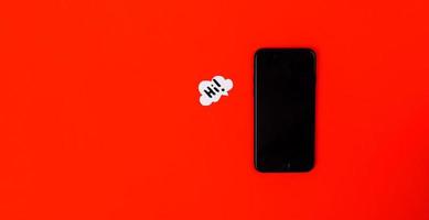 smartphone con bolle di discorso di carta su sfondo rosso foto