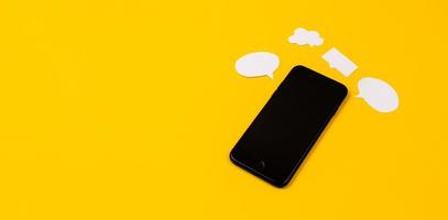 smartphone con bolle di discorso di carta su sfondo giallo