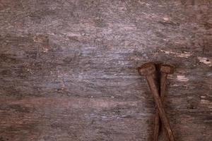 due vecchi chiodi arrugginiti poggiano su uno sfondo di legno foto
