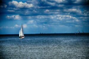 blu paesaggio con il mare e un' bianca barca a vela su il orizzonte su il disco baia nel Polonia foto