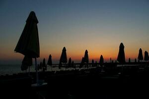 pittoresco paesaggio a tramonto di il mare con lettini e ombrelli foto