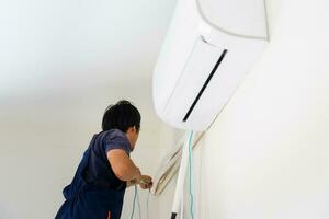 riparatore fissaggio aria condizionatore unità, tecnico uomo installazione un aria condizionata nel un' cliente Casa, Manutenzione e riparazione concetti foto