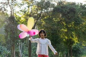 ritratto di bambino ragazza giocando con colorato giocattolo palloncini nel il parco all'aperto. foto