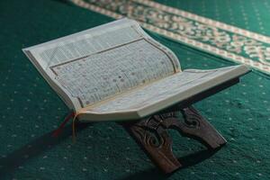 bogor, Indonesia - 2022. un' vicino su di il santo libro al-quran su un' verde preghiera tappeto. islamico foto concetto.