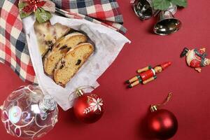 Natale natale decorazione ornamento campana regalo verificato tessuto stoffa avvolgere affettato Stollen frutta torta cibo pino frutta su rosso sfondo foto