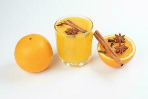 fresco arancia cannella stella anice Chiodo di garofano Spezia succo nel bicchiere su bianca giallo sfondo foto