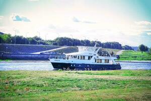 kaunas, Lituania 20 10 2022 piccolo bianca e blu nave parcheggiata vicino il riva su fiume blu acqua su il banca su soleggiato giorno foto